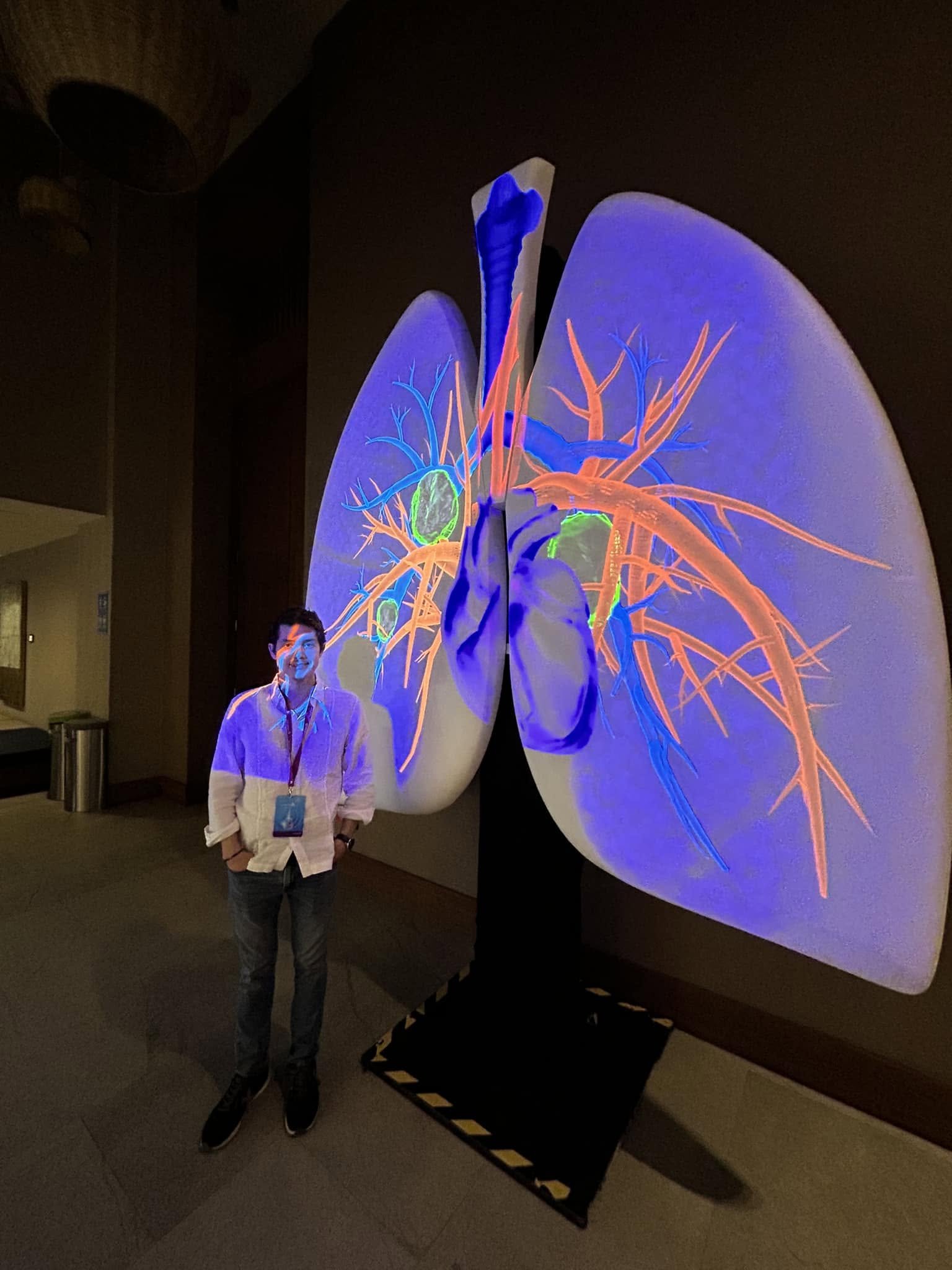 Dr. Víctor González en un evento de divulgación médica, junto a un modelo anatómico de los pulmones